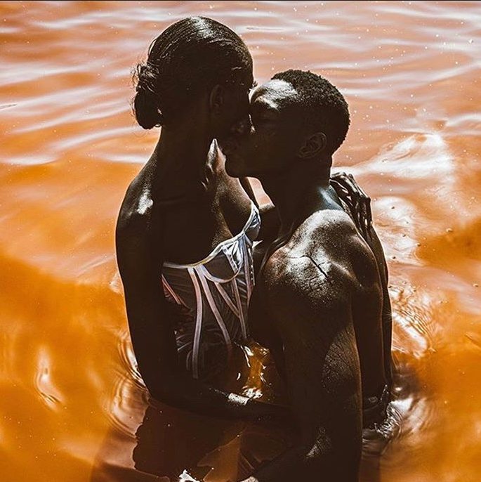  A black couple kissing in the middle of the ocean